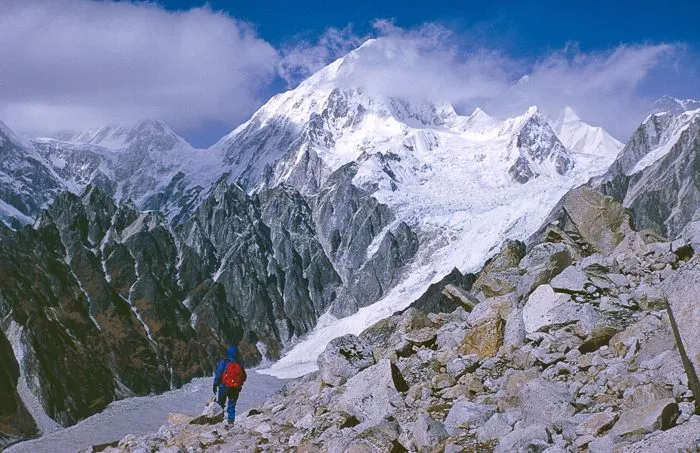A porter crosses a makeshift bridge over a tributary of the Buri Gandaki